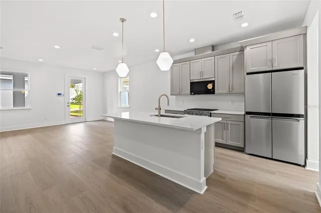 a kitchen with kitchen island a counter top space stainless steel appliances and a window