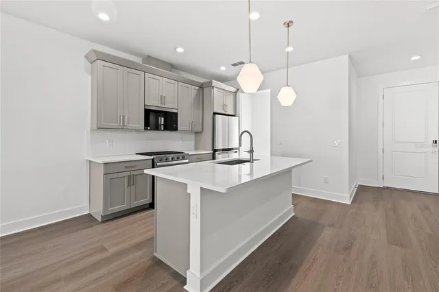 an open kitchen with wooden floor and stainless steel appliances
