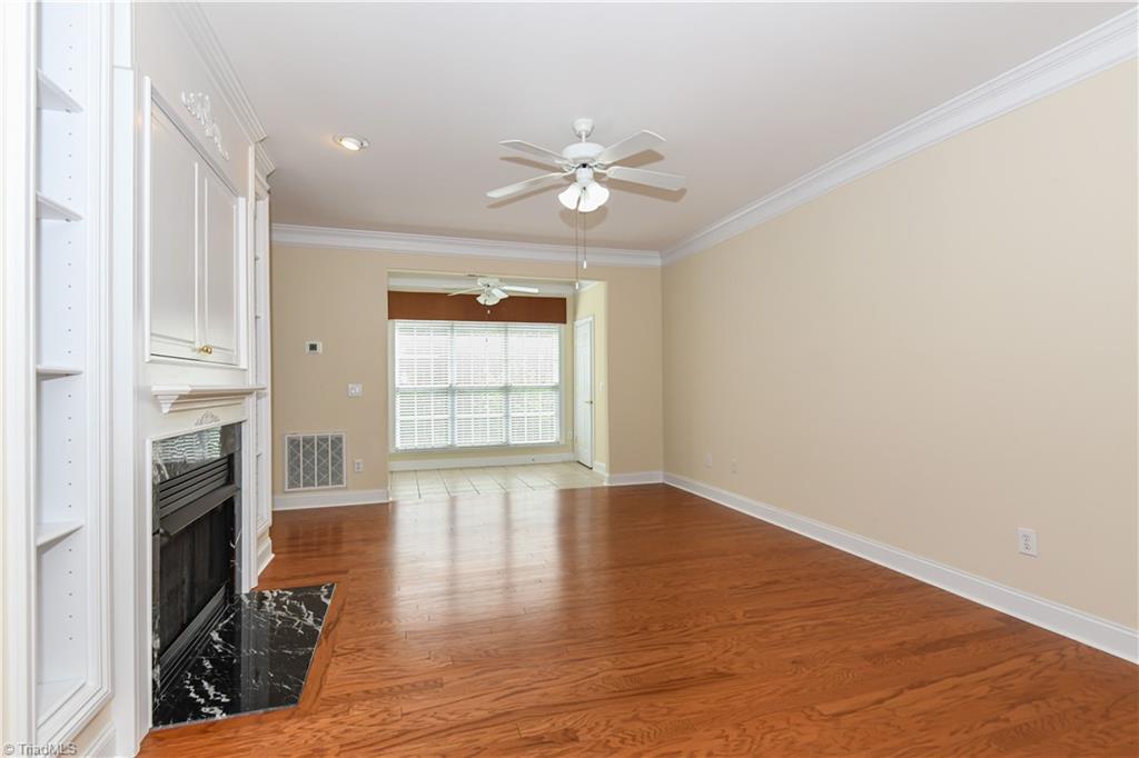 522 College Road Greensboro, NC 27410 - Photo 10 of 36 From the foyer, looking into the living room with a gas log fireplace flanked by built in cabinetry, has ample space to place your furniture. Also, notice the engineered wood flooring that the seller installed thru out in 2021 except in the foyer/kitchen/baths/laundry. The tile floor sunroom has large windows that allow the room to be bathed in natural sunlight.