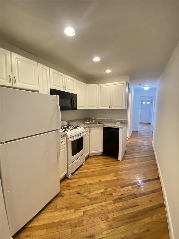 409 1st Street, Unit A Hoboken, NJ 07030 - Photo 2 of 10 a kitchen with a refrigerator a stove top oven and white cabinets