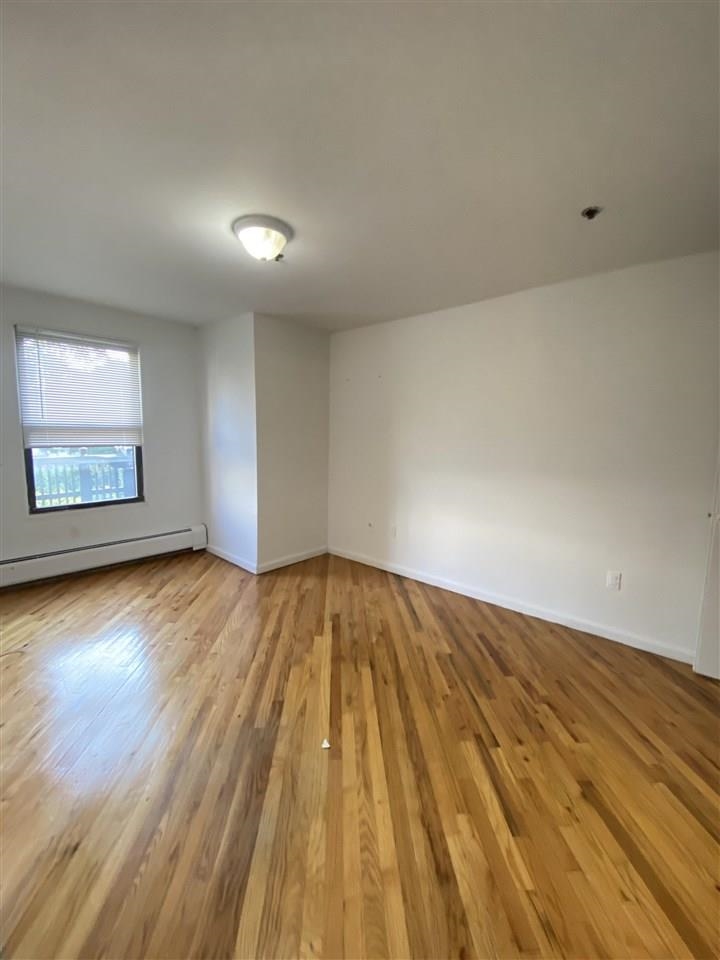 409 1st Street, Unit A Hoboken, NJ 07030 - Photo 3 of 10 an empty room with wooden floor and windows