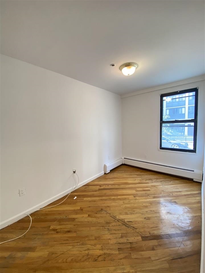 409 1st Street, Unit A Hoboken, NJ 07030 - Photo 4 of 10 wooden floor in an empty room with window