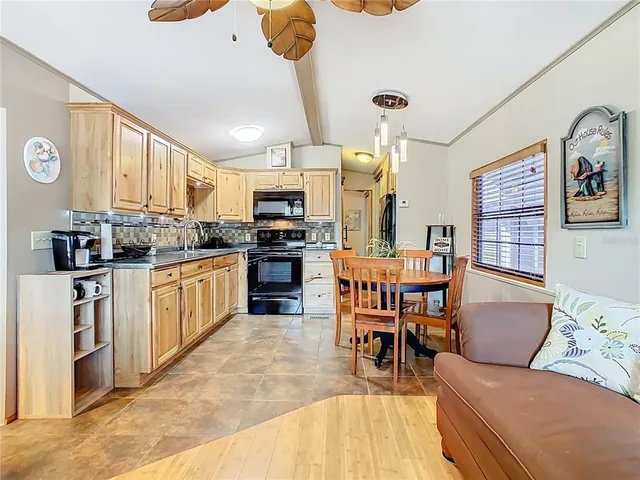 a kitchen with stainless steel appliances kitchen island granite countertop a refrigerator a stove top oven a sink dishwasher and white cabinets with wooden floor