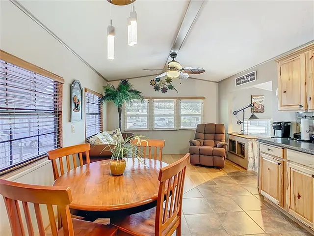 a view of a dining room with furniture a chandelier and large windows