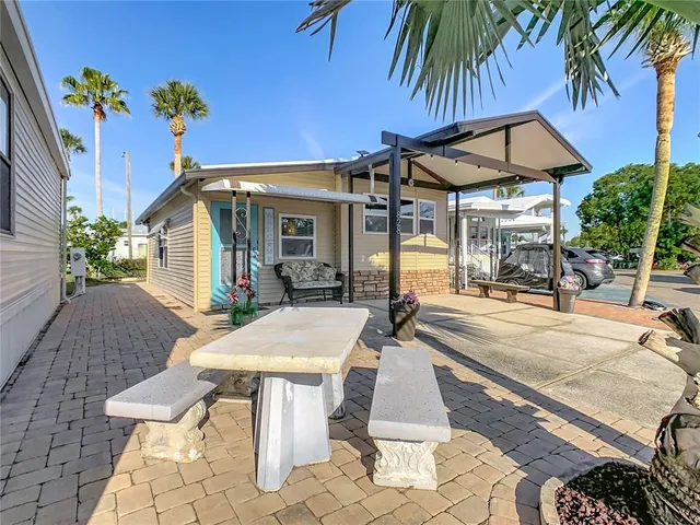 a view of a patio with table and chairs under an umbrella with potted plants