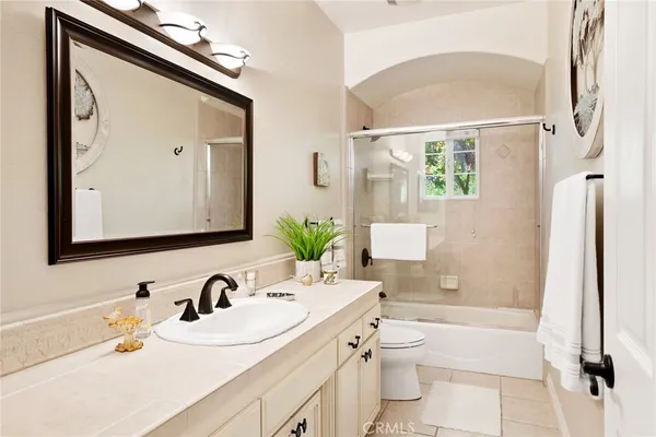 a bathroom with a granite countertop sink mirror vanity bathtub and a toilet