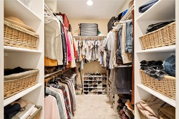 a view of walk in closet with clothes and shoes