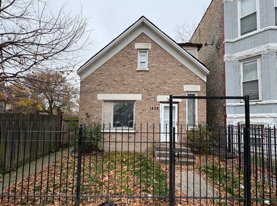 a view of a brick house with a small yard and wooden fence