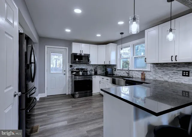 a kitchen with kitchen island granite countertop a stove sink cabinets and refrigerator