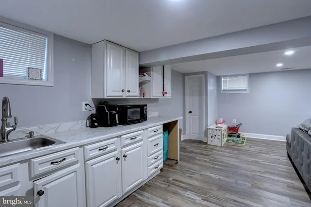 a living room with stainless steel appliances furniture a kitchen view and wooden floor