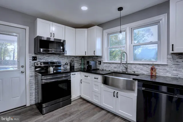 a kitchen with granite countertop a sink wooden cabinets and stainless steel appliances