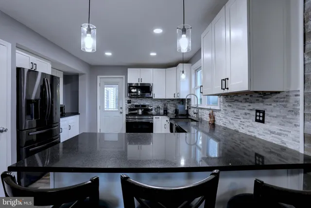 a kitchen with a dining table chairs stainless steel appliances and cabinets