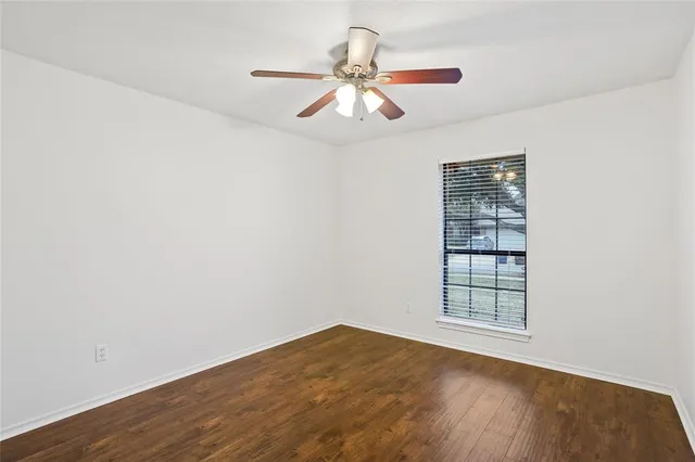 an empty room with wooden floor closet and windows