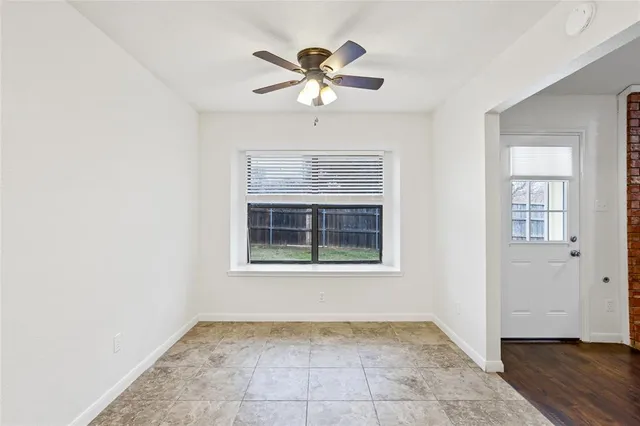 an empty room with chandelier fan and windows