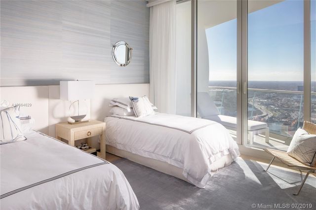 a bedroom with two beds and glass door