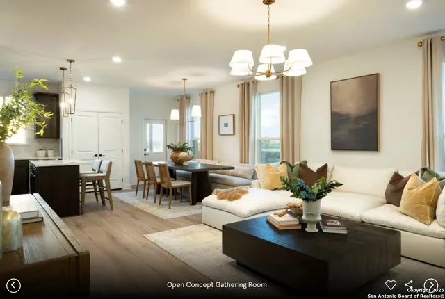a living room with furniture a chandelier and a view of kitchen