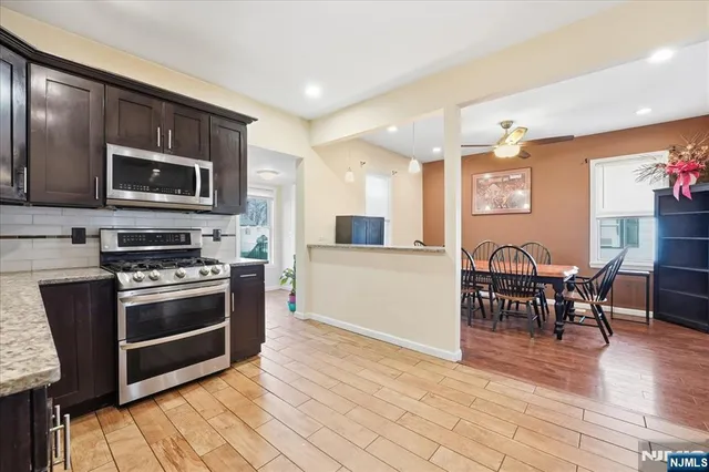 a kitchen with stainless steel appliances kitchen island granite countertop a stove top oven a sink a dining table and chairs