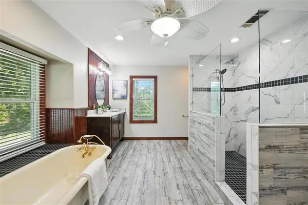 a spacious bathroom with a tub sink and mirror