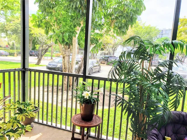 a view of an apartment building with a big yard and large trees