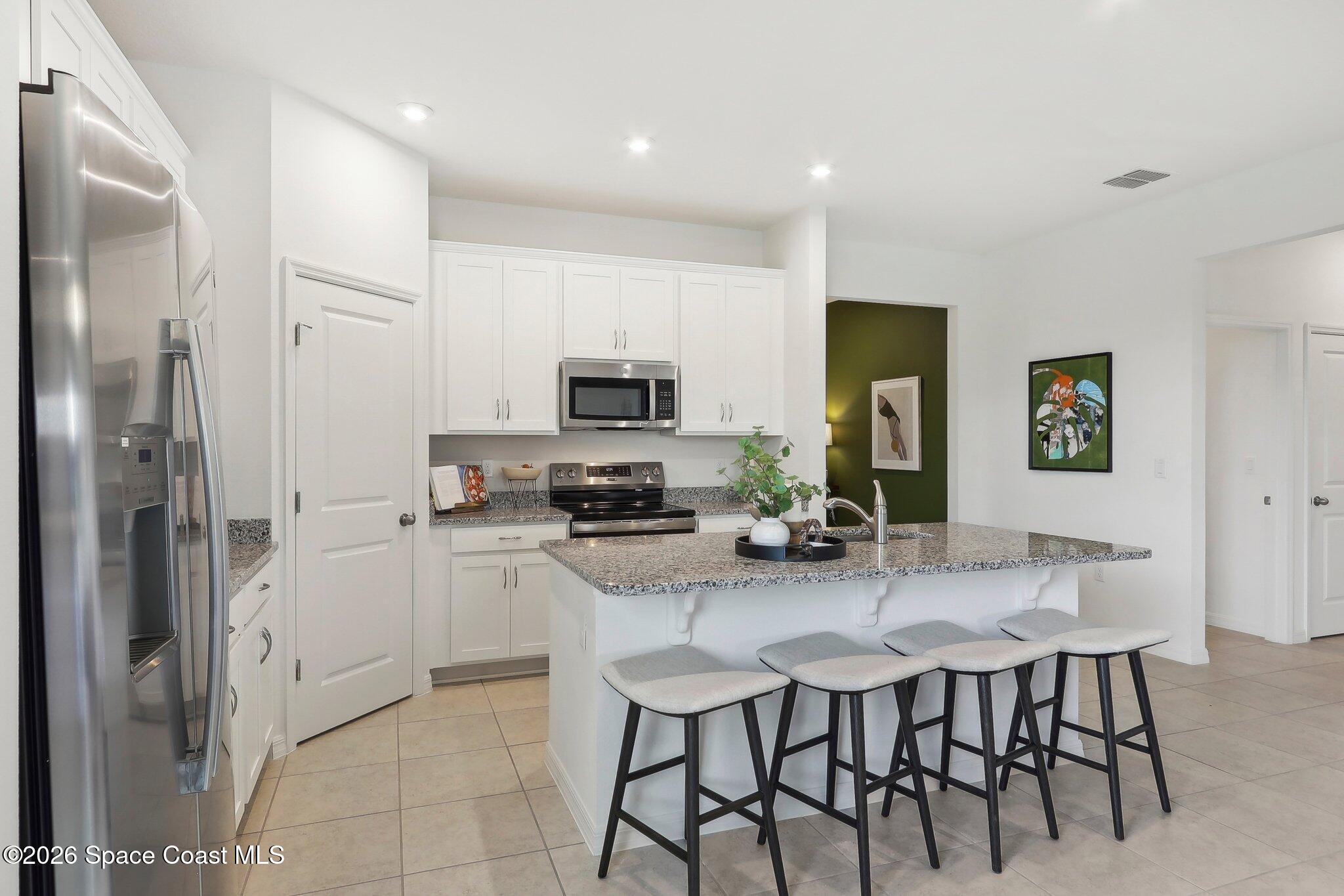 1332 Dunblane Way Northeast Palm Bay, FL 32905 - Photo 13 of 32 a kitchen with a table chairs refrigerator and cabinets