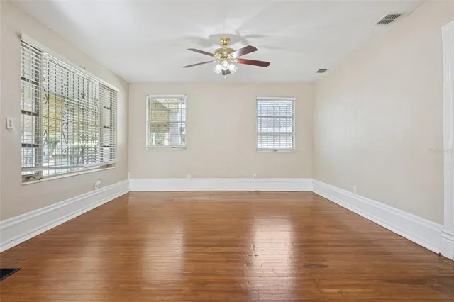 a view of an empty room with wooden floor and a window
