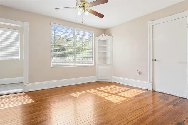 a view of an empty room with wooden floor and a window