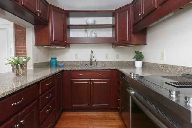 a kitchen with stainless steel appliances granite countertop wooden cabinets a stove top oven a sink and dishwasher