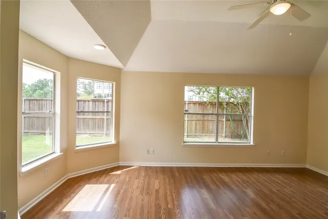 a view of an empty room with wooden floor and a window