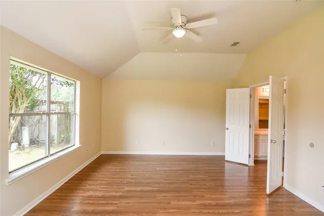 a view of empty room with wooden floor and fan