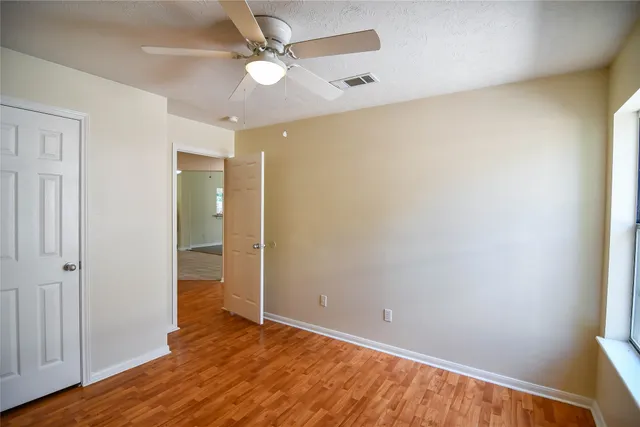 an empty room with wooden floor and a ceiling fan