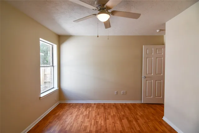 a view of an empty room with window and wooden floor