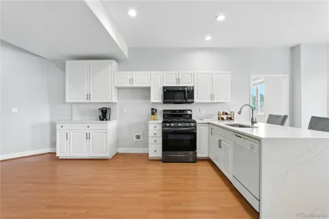 a kitchen with stainless steel appliances a stove top oven a sink a refrigerator and white cabinets