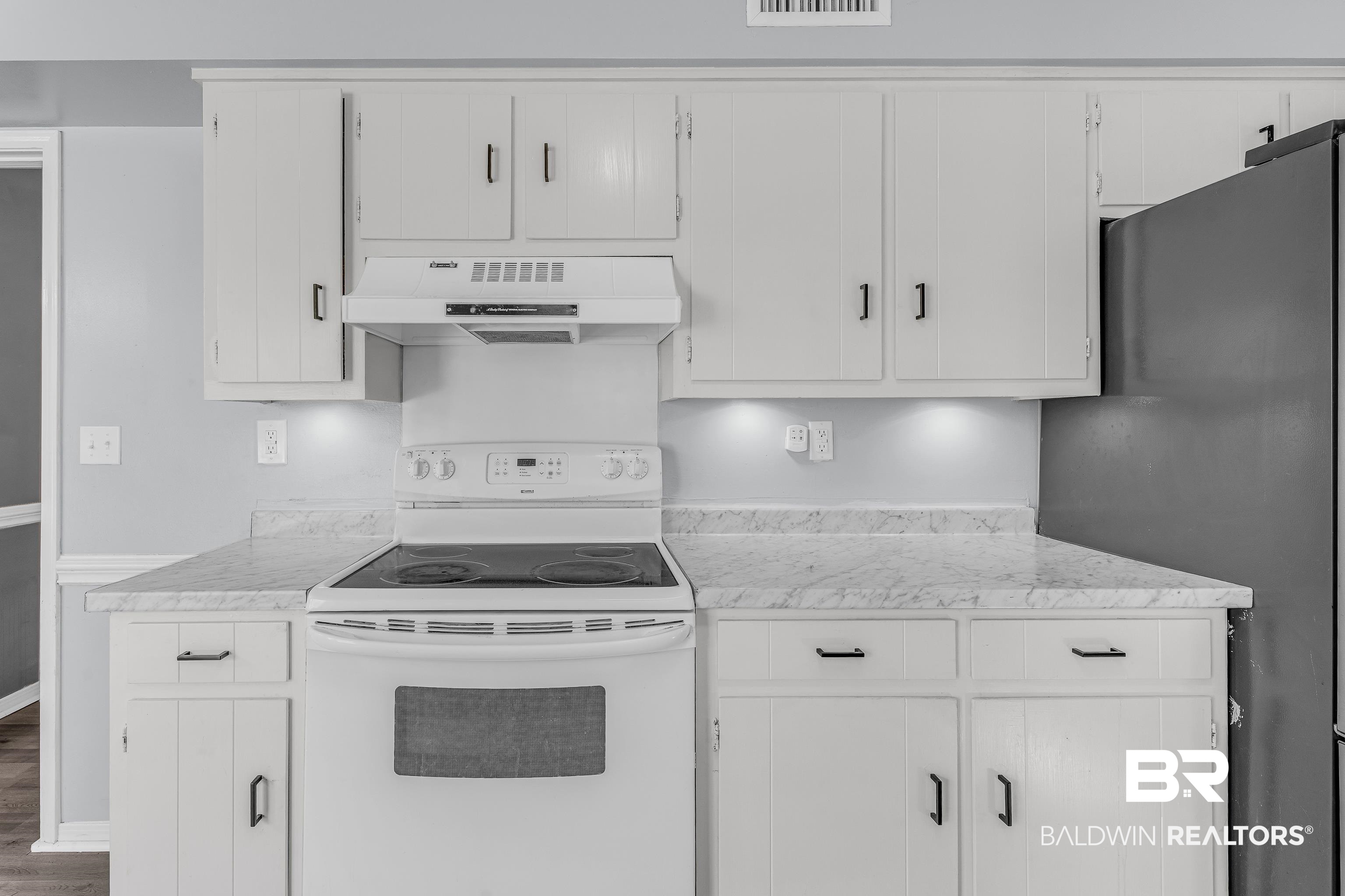 6135 Oak Cliff Drive Eight Mile, AL 36613 - Photo 13 of 30 Kitchen featuring white electric range, freestanding refrigerator, light countertops, under cabinet range hood, and white cabinets
