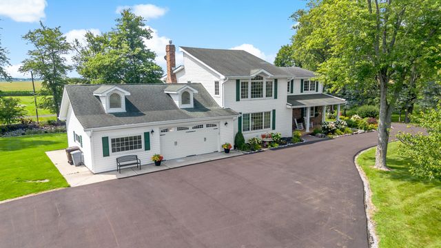 a front view of a house with a garden and a tree
