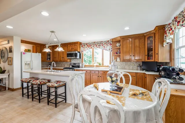 a kitchen with stainless steel appliances granite countertop a stove a sink a dining table and chairs