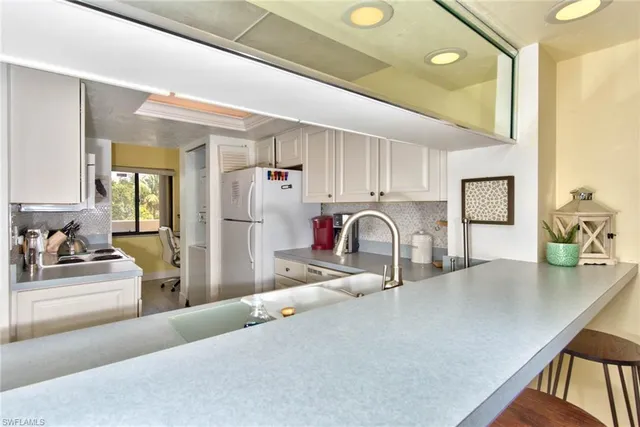 a view of a kitchen with kitchen island a sink stainless steel appliances and cabinets