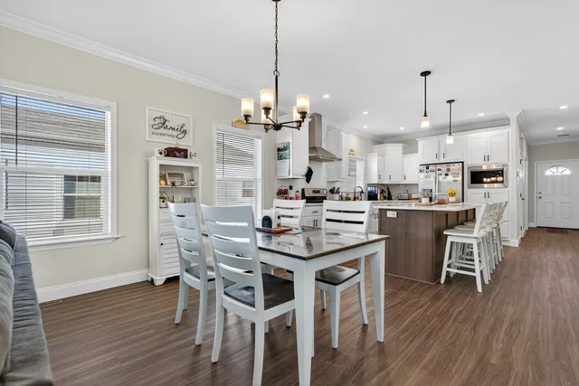 a kitchen with stainless steel appliances kitchen island granite countertop a dining table chairs and white cabinets