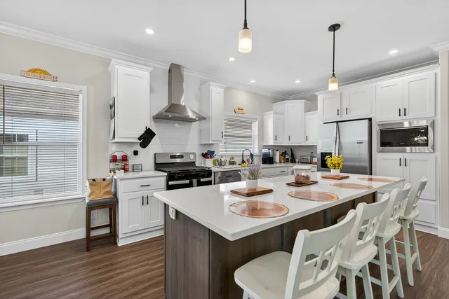 a kitchen with stainless steel appliances kitchen island granite countertop a sink a stove a dining table and chairs