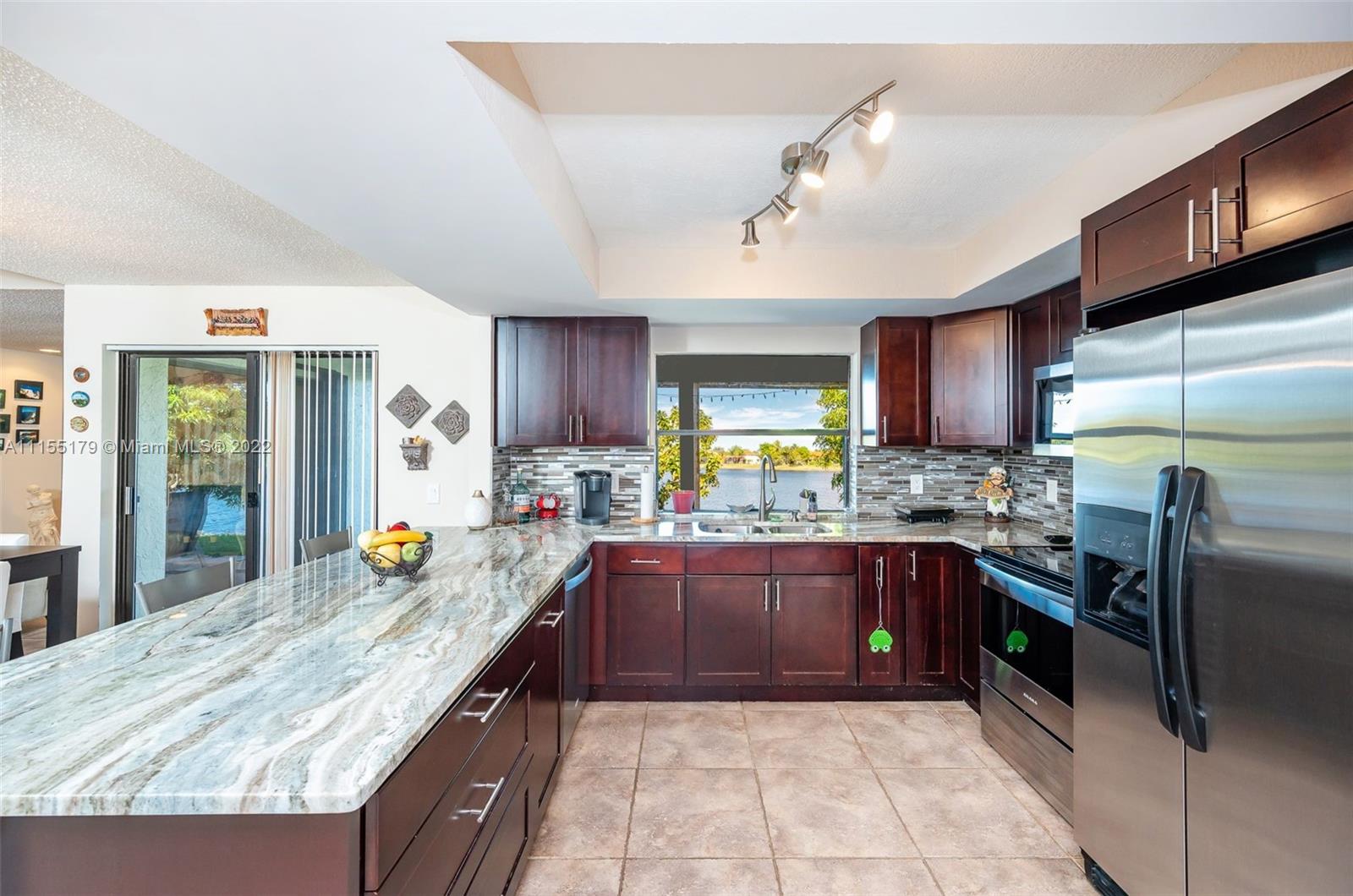 14853 Southwest 42nd Lane Miami, FL 33185 - Photo 11 of 28 a kitchen with stainless steel appliances granite countertop sink stove refrigerator and cabinets