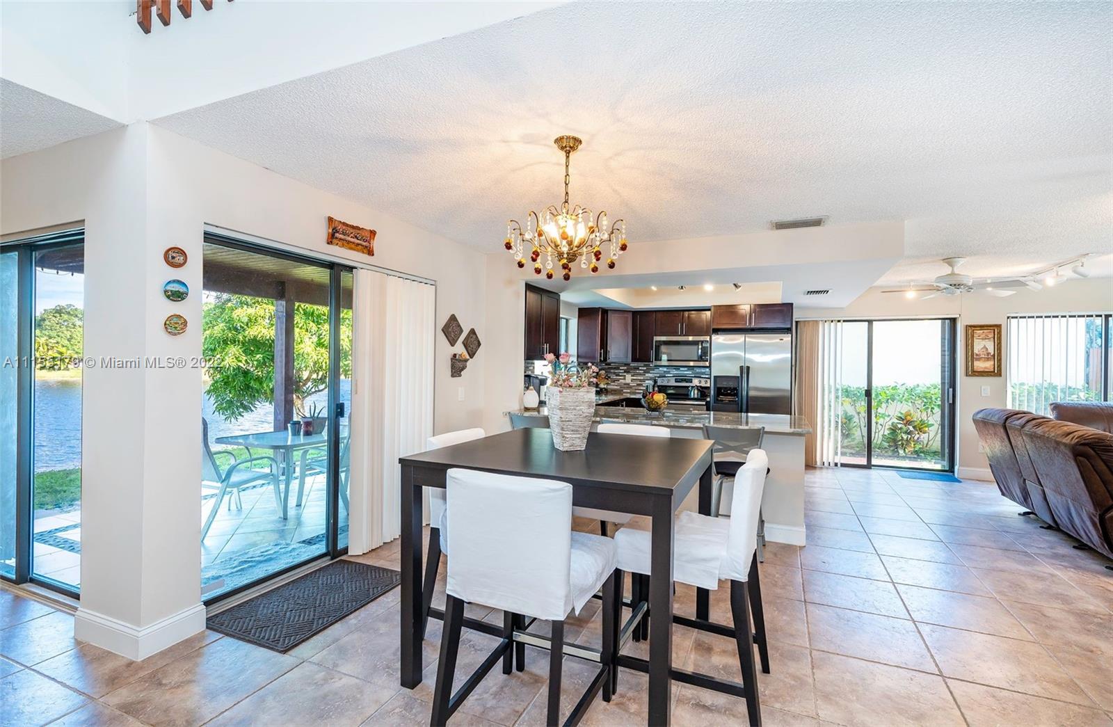 14853 Southwest 42nd Lane Miami, FL 33185 - Photo 12 of 28 a dining room with wooden floor a chandelier a wooden table and chairs