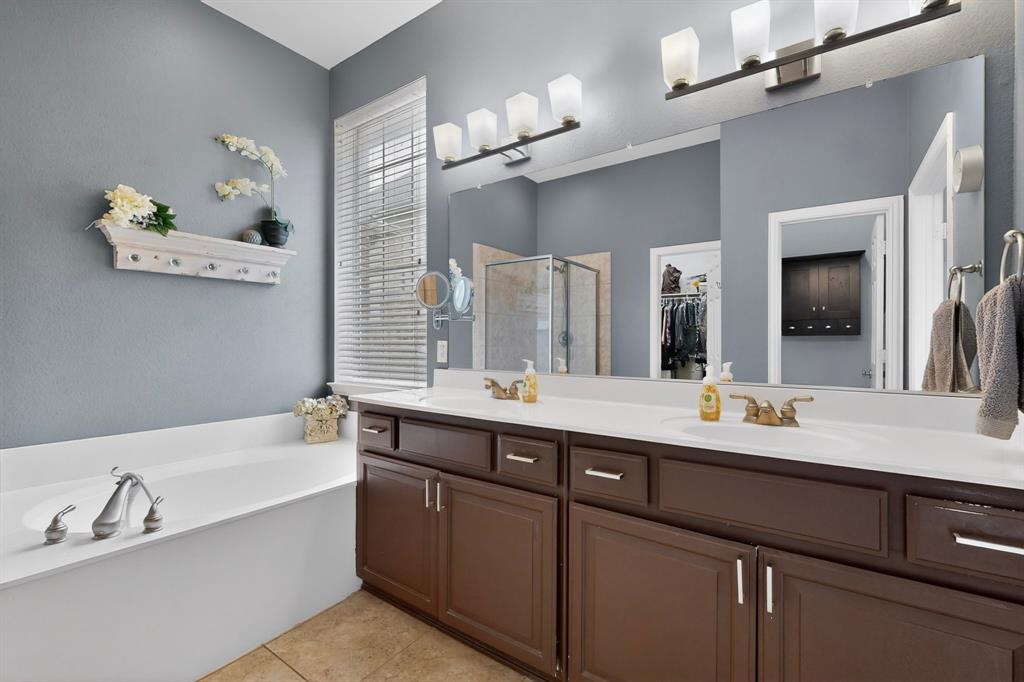 4004 White Porch Road Plano, TX 75024 - Photo 24 of 40 a bathroom with a double vanity sink a large mirror and a bathtub