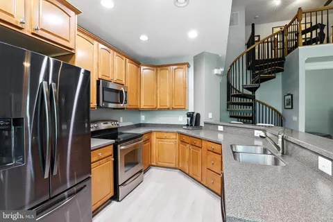 a kitchen with stainless steel appliances granite countertop a sink a stove a refrigerator and cabinets