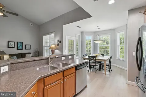 a dining hall with stainless steel appliances granite countertop a dining table and chairs