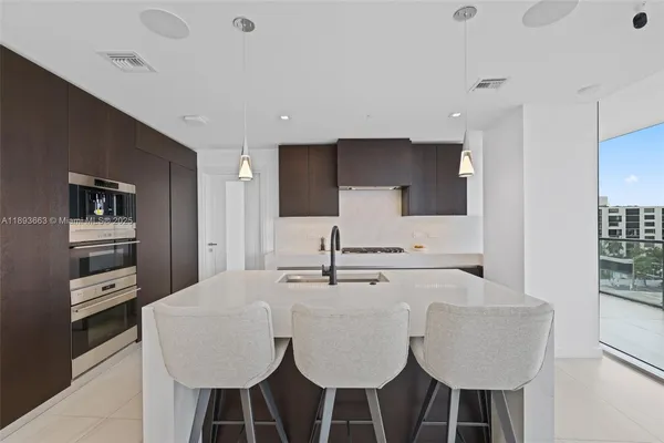 a kitchen with kitchen island granite countertop a sink cabinets and refrigerator
