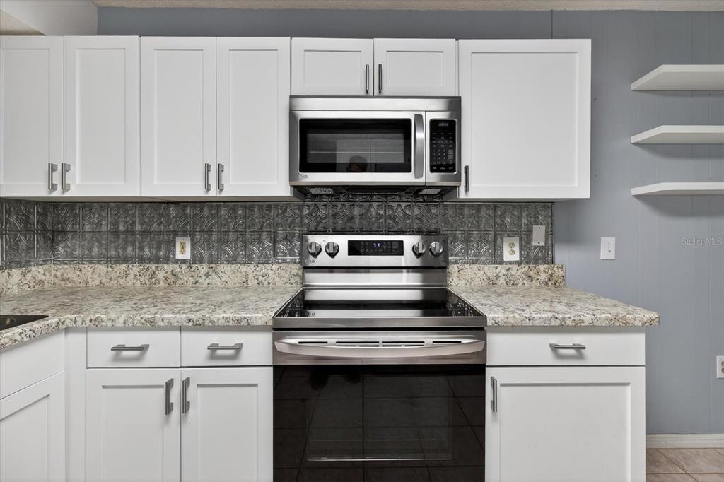 7802 Hardwick Drive, Unit 1116 New Port Richey, FL 34653 - Photo 19 of 73 a kitchen with granite countertop white cabinets and stainless steel appliances