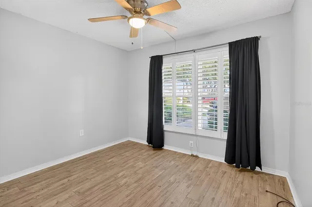 a view of an empty room with a window and wooden floor