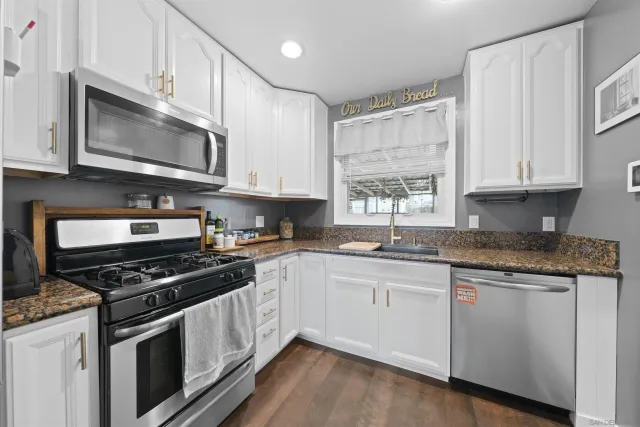 a kitchen with stainless steel appliances granite countertop a stove a sink and a microwave