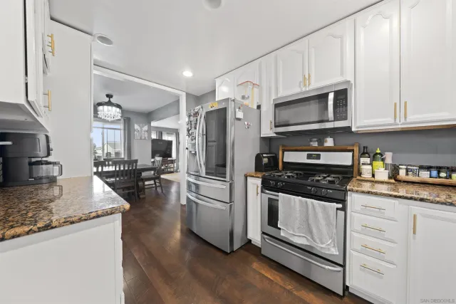 a kitchen with granite countertop a refrigerator stove and sink