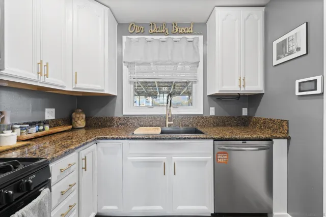 a kitchen with granite countertop a sink stove and cabinets