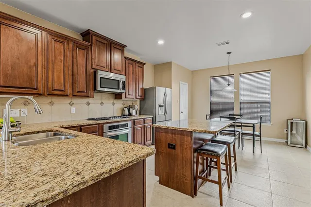 a kitchen with stainless steel appliances granite countertop a stove a sink dishwasher and cabinets with wooden floor